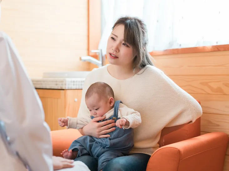 赤ちゃんを抱いて腰が痛そうな女性